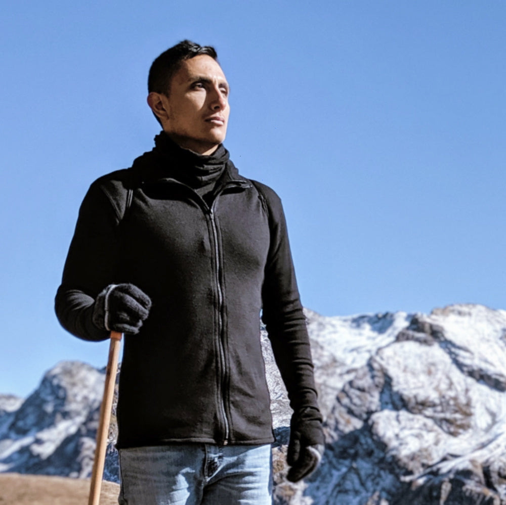 man wearing alpaca wool base layer hiking in front of snowy mountains